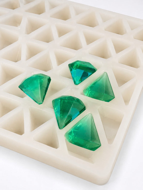 Smaragdgrüne diamantförmige Fruchtgummis neben einer gewerblichen Silikonform zum Rezepturvergleich